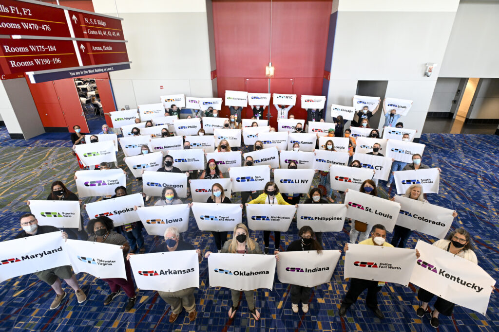 CSTA Chapter leaders stand in a group holding signs that designate their chapter.