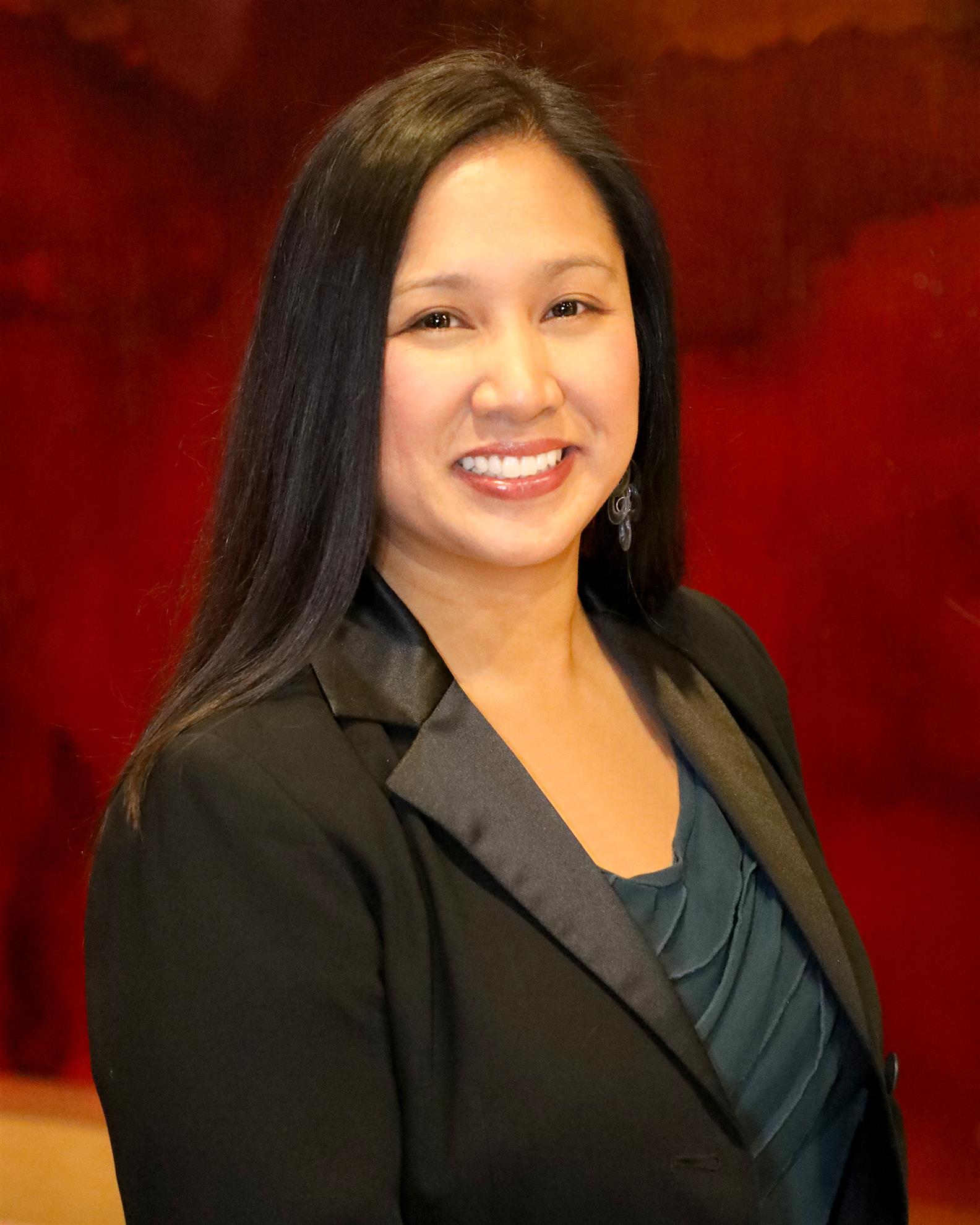 Headshot of Lilibeth Mora, a medium-light skinned woman with long, straight black hair and a black blazer over a blouse. 