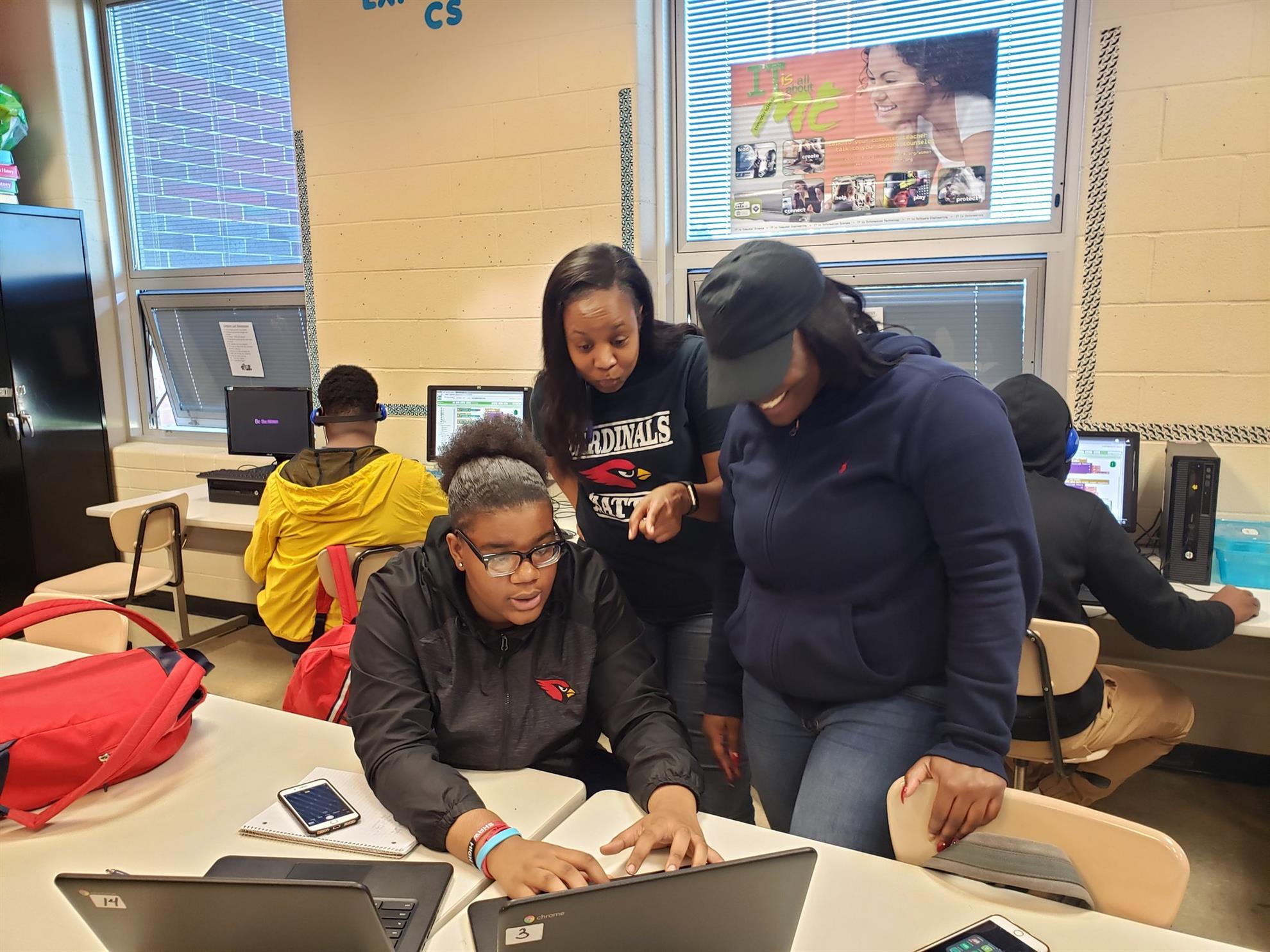 A teacher is helping a student at a laptop